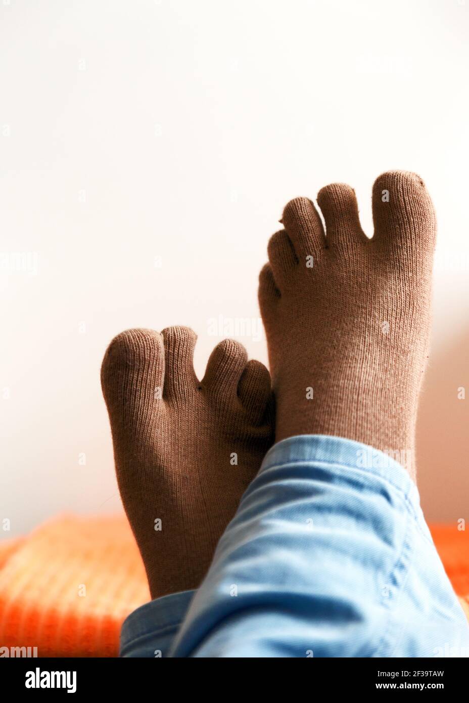 Nahaufnahme der überkreuzten Füße eines Mannes mit Zehensocken Stockfoto
