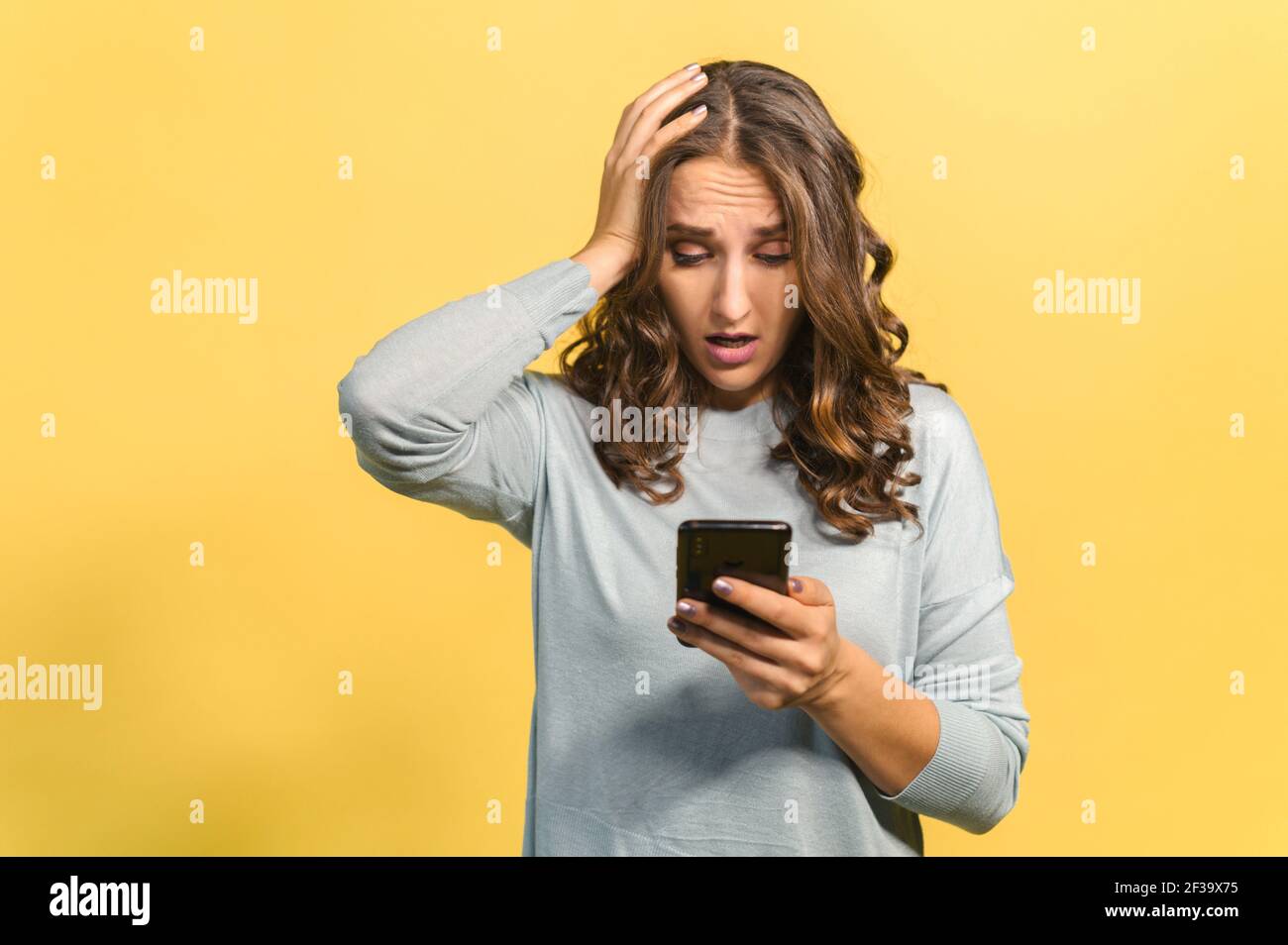 Schockiert Lockig Brünette Junge Frau Hält Smartphone, Blick Auf Handy-Bildschirm  Und Hat Enttäuschung Gesicht, Erhielt Eine Schlechte Nachricht, Einen  Fehler Gemacht Und Ein Telefon Ist Gesperrt, Isoliert Auf Gelb  Stockfotografie - Alamy