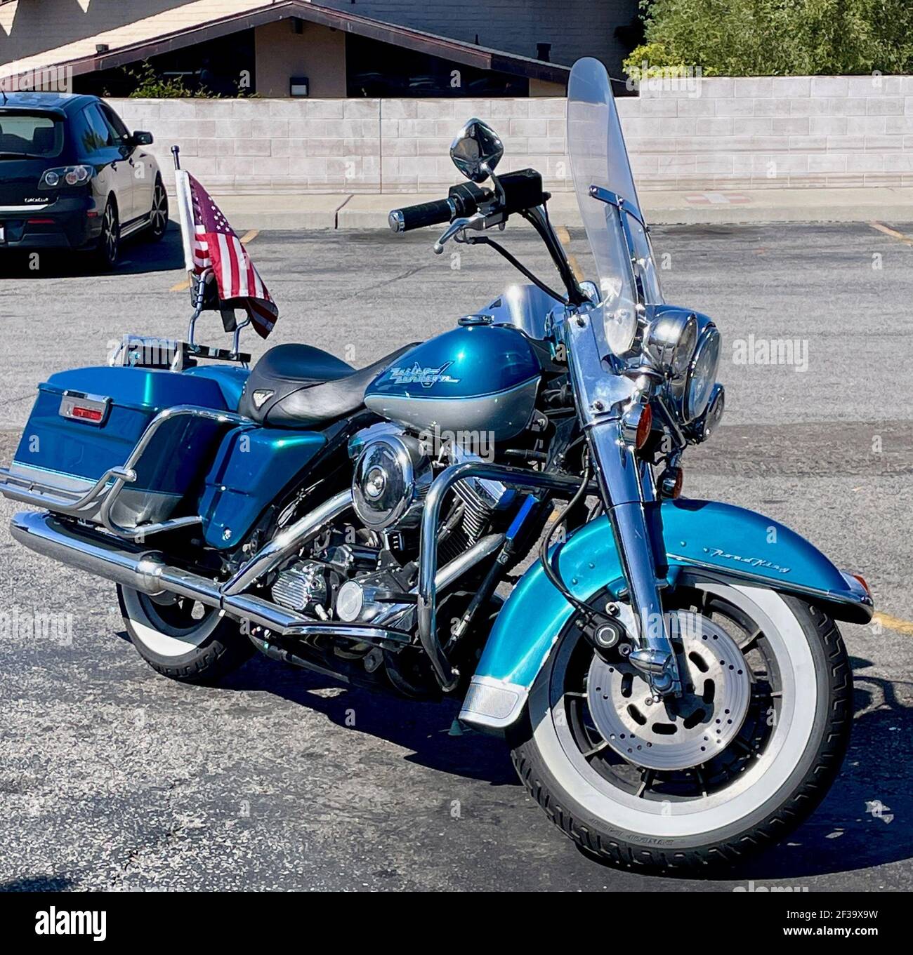 FRESNO, USA - Mar 01, 2021: Ein Nahaufnahme Foto von einem glänzenden Harley Davidson Road King mit weißen Wandreifen geparkt mit einer amerikanischen Flagge auf der Stockfoto
