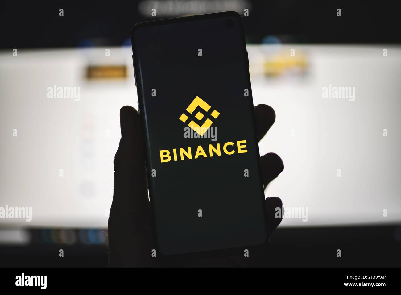 Mann hält ein Smartphone mit Binance-Logo mit verschwommener Website als Hintergrund. Kryptowährungsbörse, Handelsplattform Stockfoto
