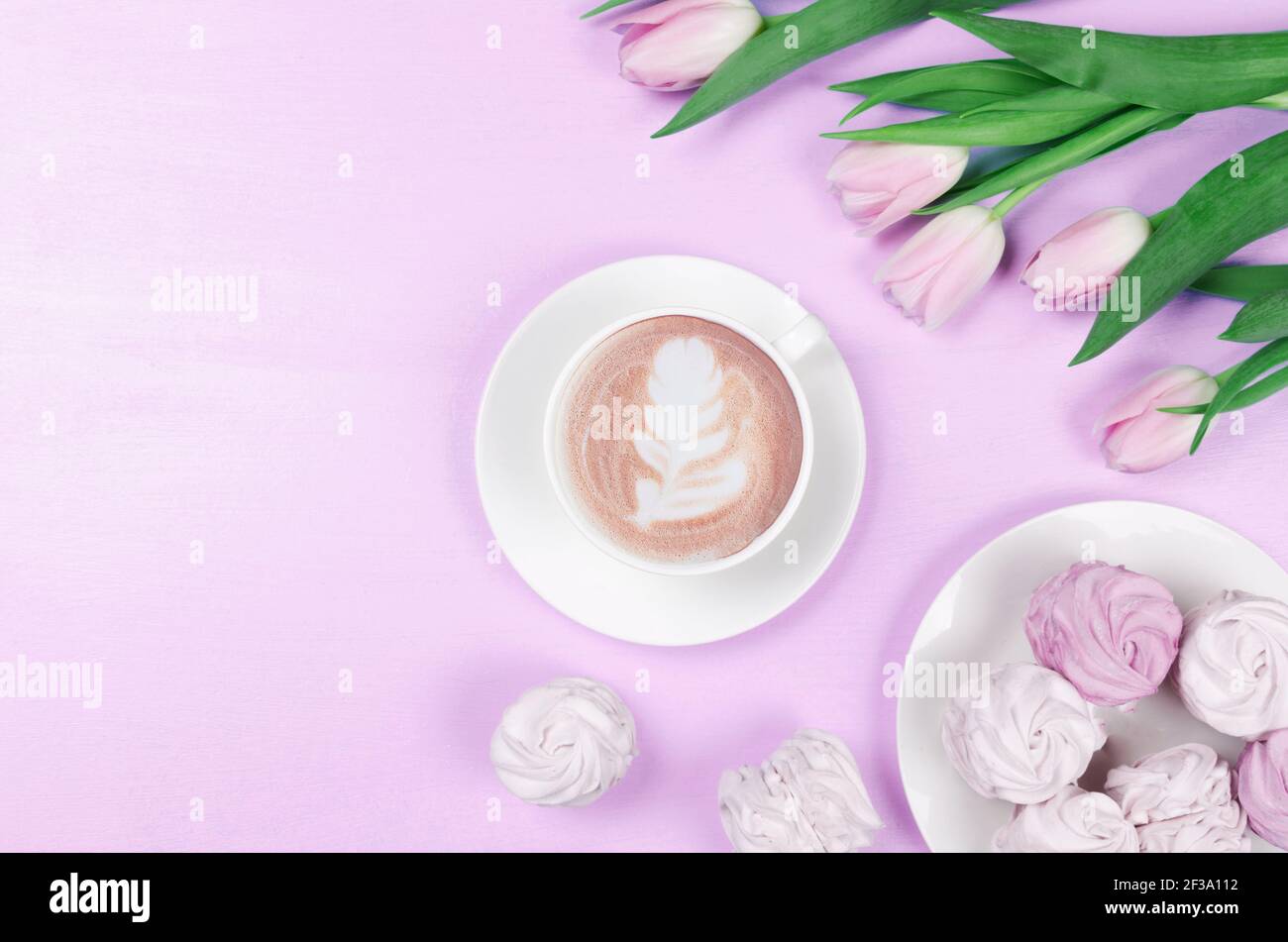 Spring Flat Lay.Weiße Tasse mit Kaffee, rosa Tulpen und Marshallows. Copy Space Stockfoto