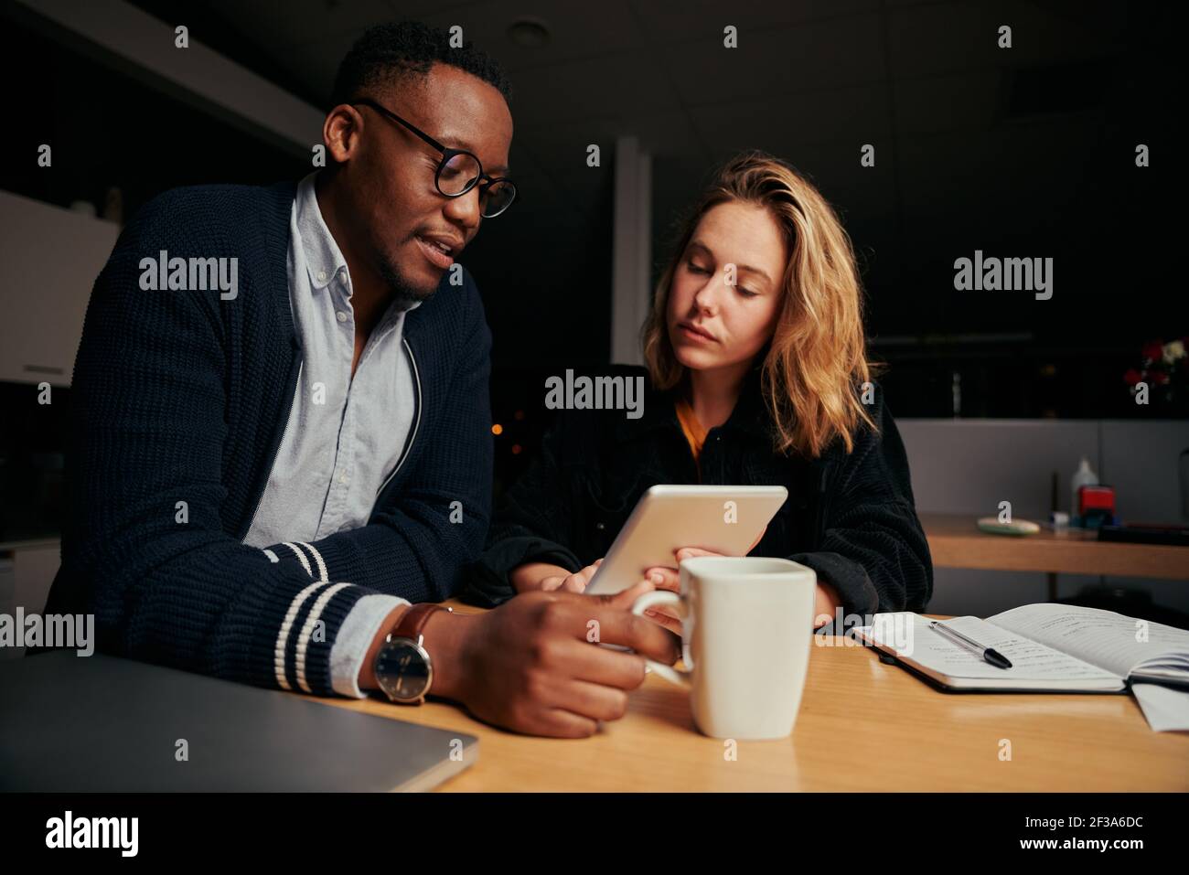 Zwei verschiedene Geschäftsleute, die sich am digitalen Tablet-PC angeschaut haben Schreibtisch im Büro Stockfoto
