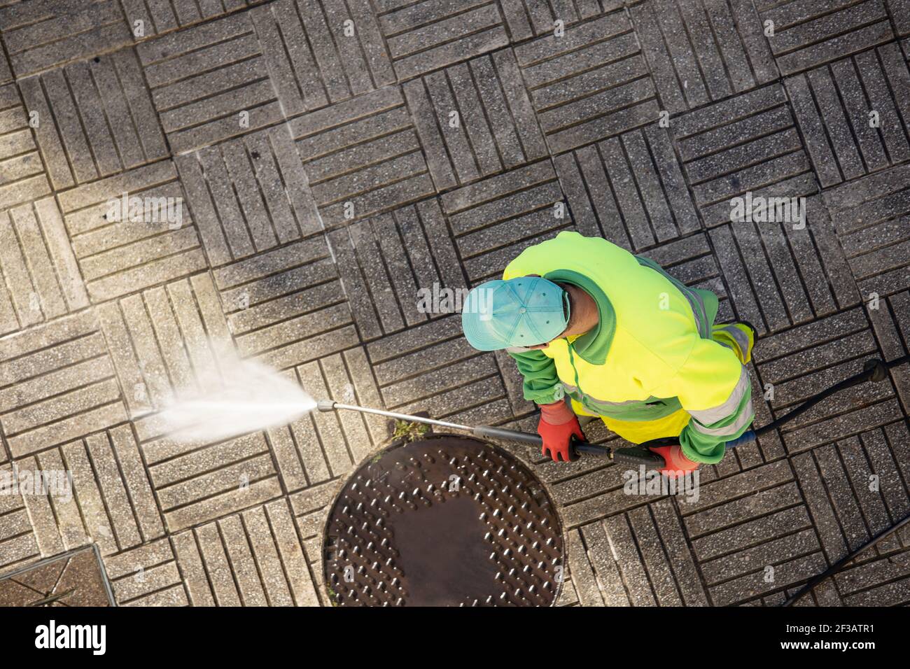 Arbeiter, die an sonnigen Tagen einen Straßenweg mit Hochdruckwasserstrahlmaschine reinigen. Speicherplatz kopieren. Draufsicht Stockfoto