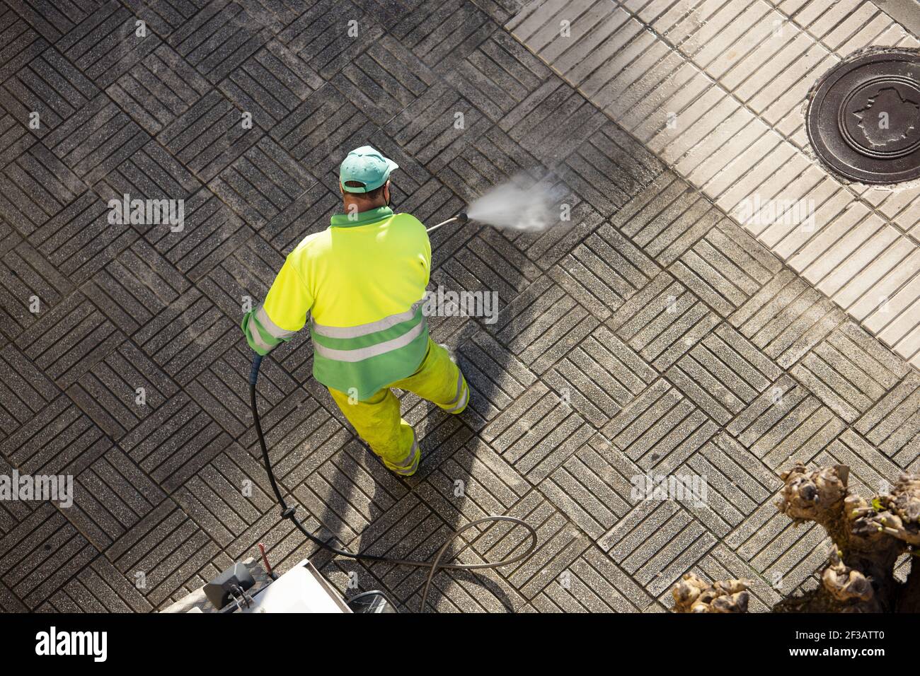 Arbeiter, die an sonnigen Tagen einen Straßenweg mit Hochdruckwasserstrahlmaschine reinigen. Speicherplatz kopieren. Draufsicht Stockfoto