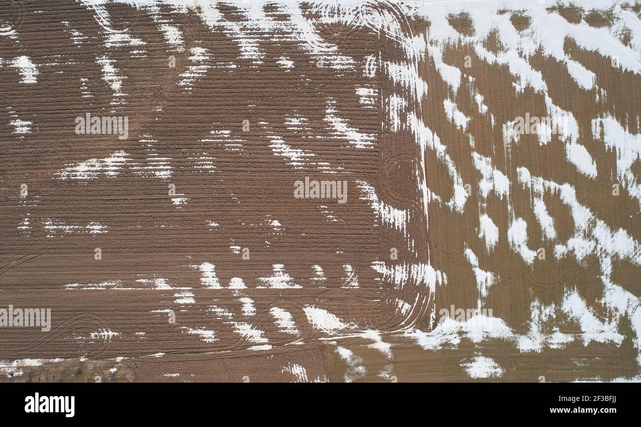 Landwirtschaftsfeld mit Schneeflecken Luftaufnahme über Drohne Draufsicht Stockfoto