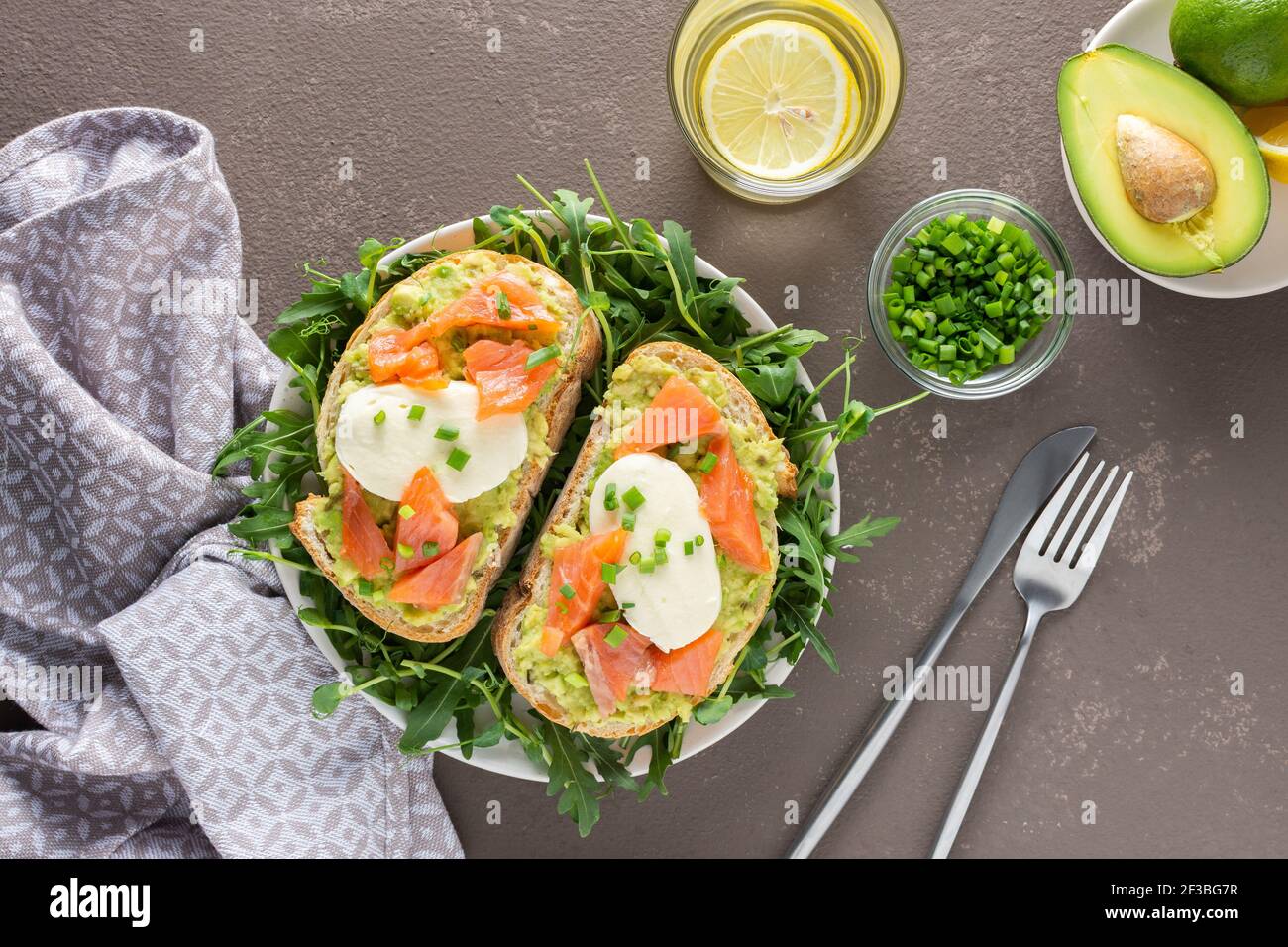 Leckeres herzhaftes Frühstück, Sandwiches mit Avocado-Paste, Lachs und Mozzarella auf einem Teller mit Rucola und Erbsensprossen Stockfoto