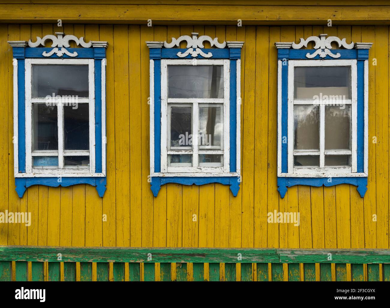 Alte Holzhütte und Hütte in blau und gelb mit Blumen in Urals, Russland. Stockfoto