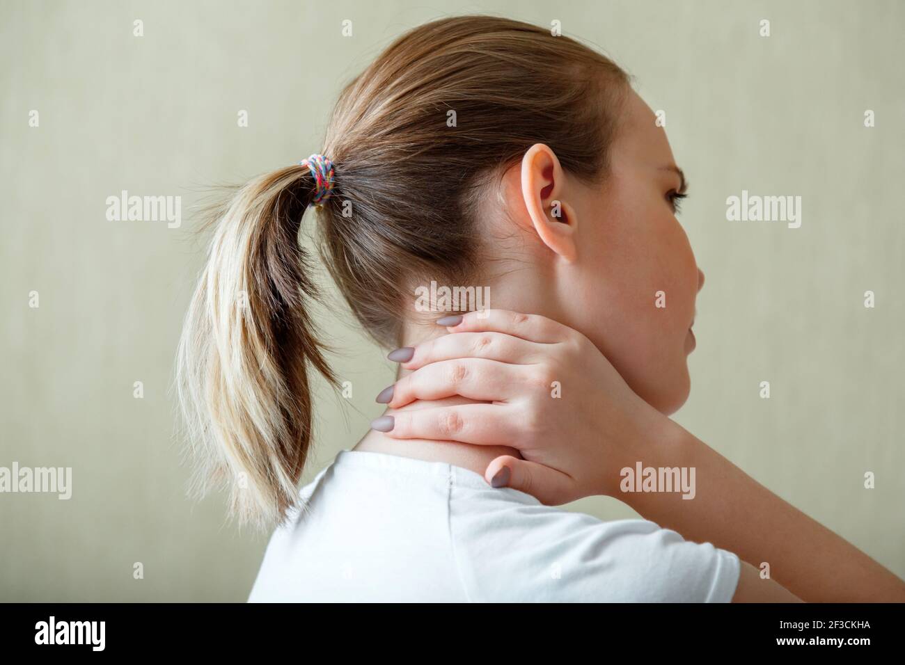 Nackenschulterschmerzen, Halswirbel. Frau hält Hals mit Schmerzen Halsmuskelkrampf von Hand. Erkrankung des Bewegungsapparates bei jungen Frauen. Er Stockfoto