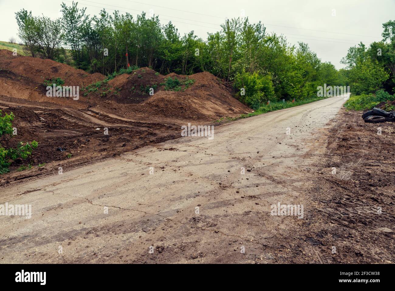 Schlammwege auf einer Straße, von der sie zurückgelassen worden waren Baufahrzeuge auf einer Straße und kann ernste Gefahr verursachen Für Fahrer Stockfoto