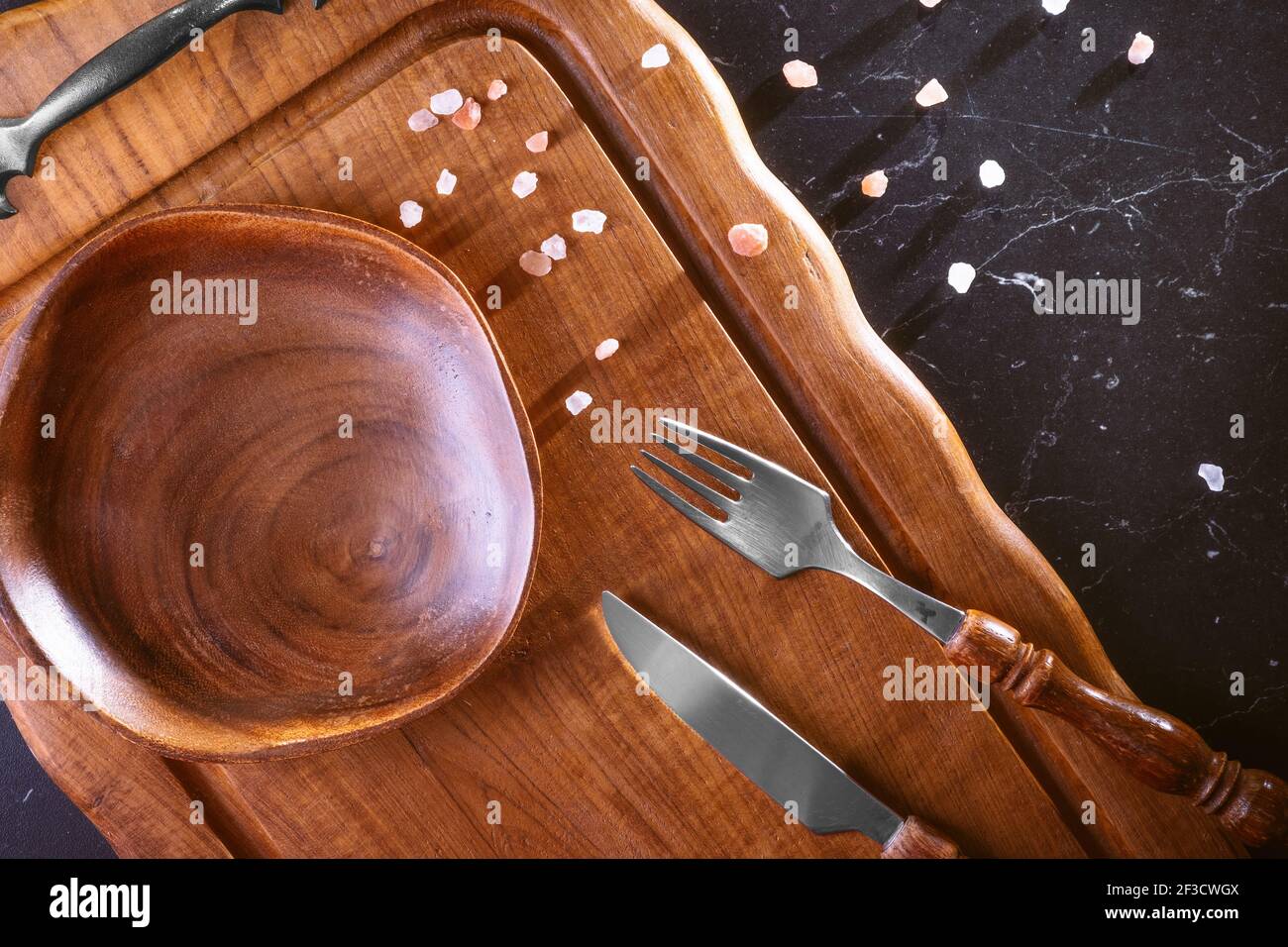 Leerer Holzteller auf einem Holztisch mit Besteck. Stockfoto