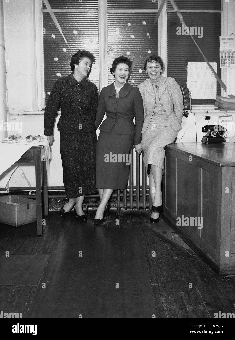 1950s, historisch, drei junge Damen des Schreibpools, die zusammen für ihr Bild stehen und lachen, bei der Hepworths Bekleidungsfirma, Clay Pit Lane, Leeds, England, UK, Tragen Sie die stilvollen femininen Outfits der Ära. Stockfoto