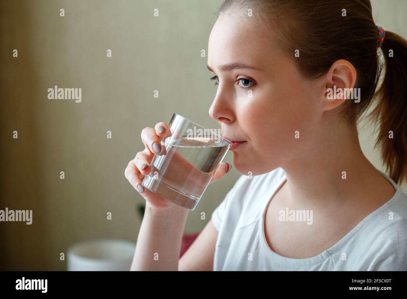 Junge Frau trinkt morgens nach dem Aufwachen ein Glas reines Wasser. Happy  teen Mädchen hält Wasserhaushalt für die Gesundheit des Körpers durch das  Trinken einer transparenten c Stockfotografie - Alamy