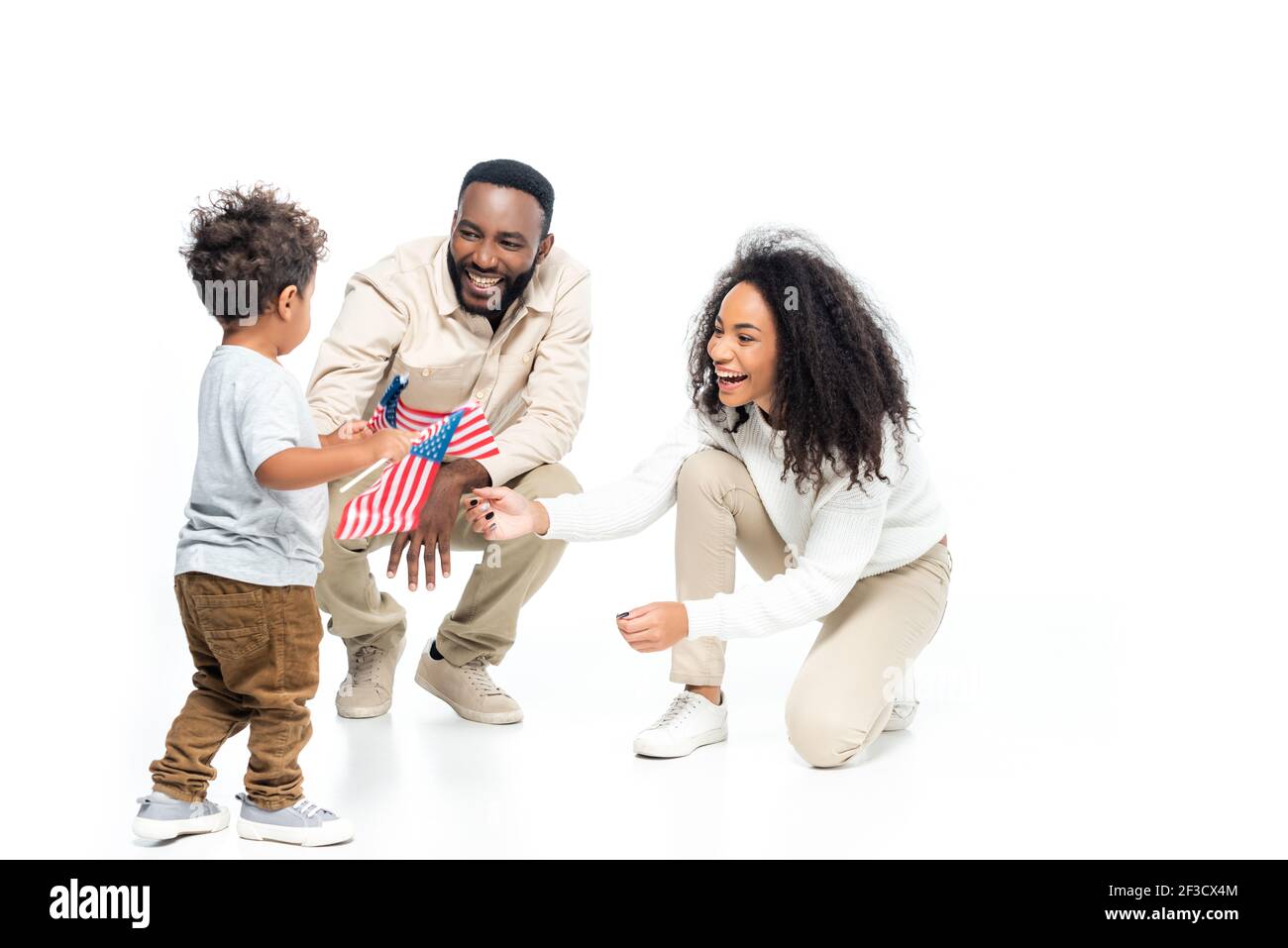 afroamerikanischer Junge hält kleine Fahnen der usa nahe lachend Eltern n weiß Stockfoto