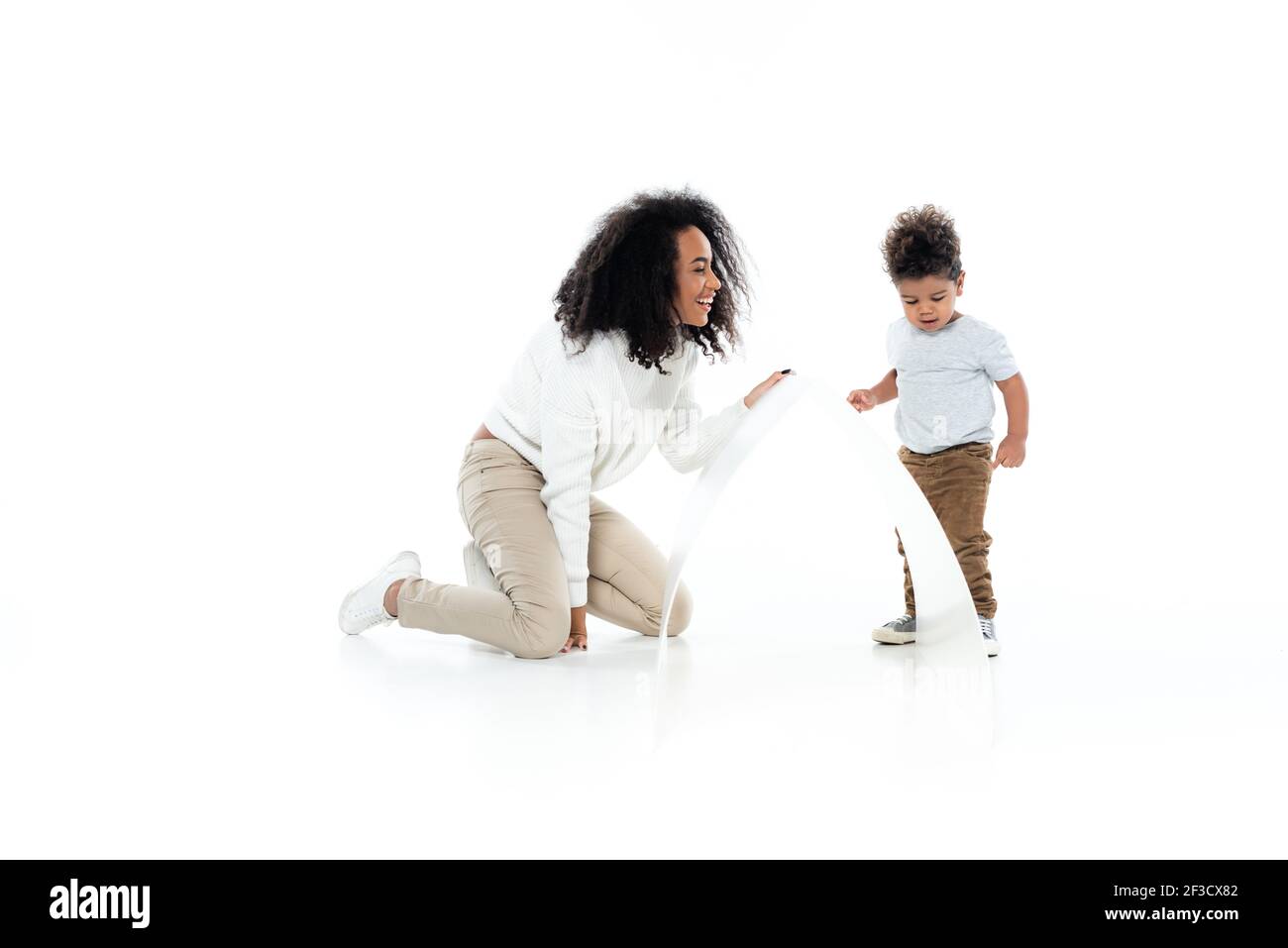 Volle Länge Ansicht der fröhlichen afroamerikanischen Frau und Kleinkind Sohn neben Papierdach auf weiß Stockfoto
