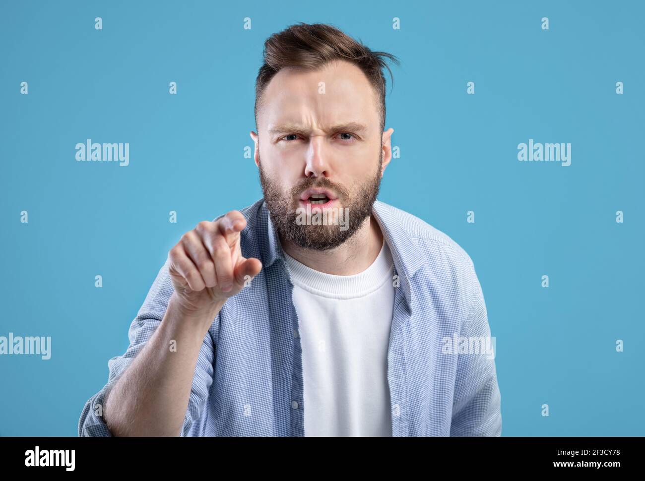 Es ist Ihre Schuld. Wütender kaukasischer Mann, der mit dem Finger auf den Bildschirm zeigt, in Anschuldigung auf blauem Studiohintergrund Stockfoto