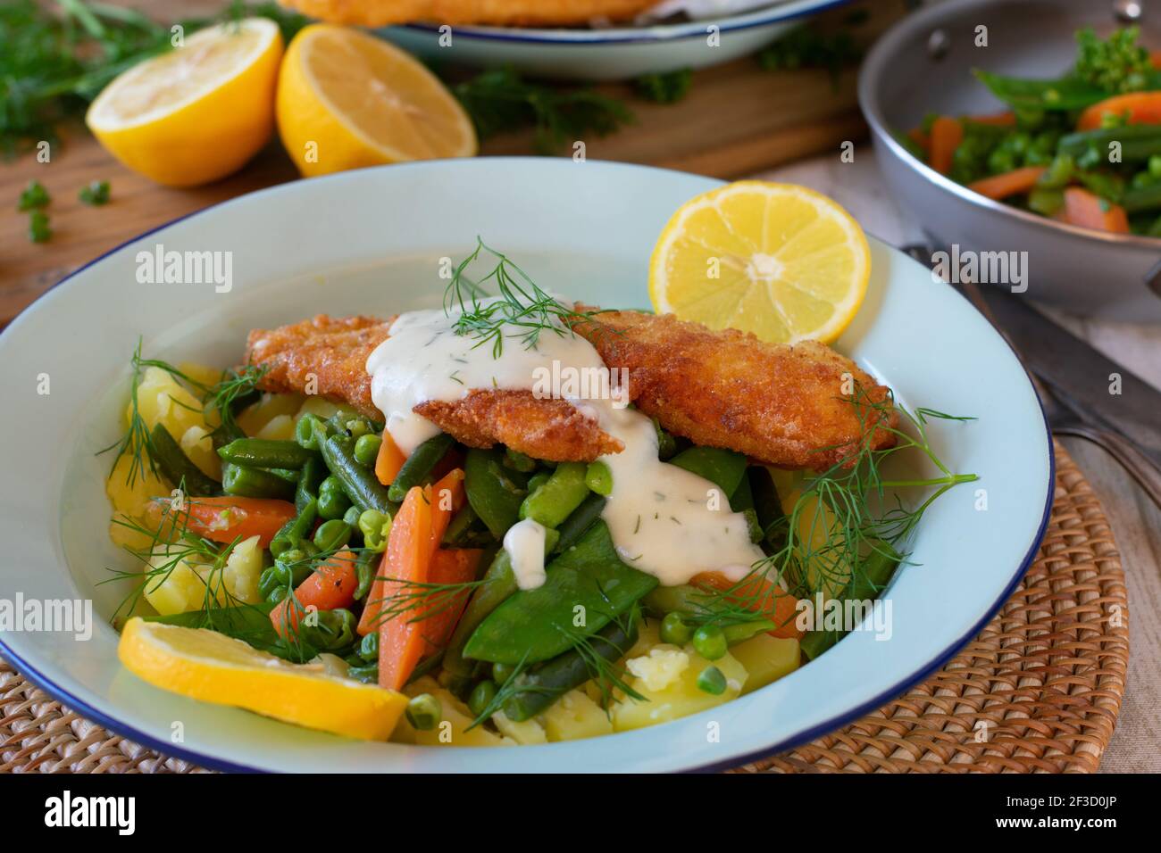 Fischgericht mit Gemüse, Kartoffeln und Sauce auf einem Teller Stockfoto