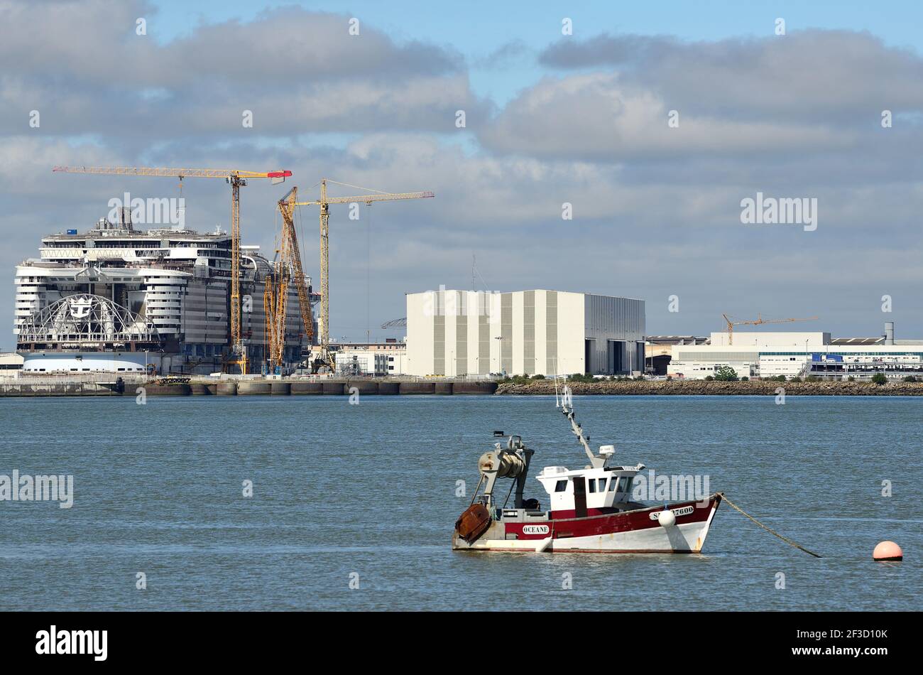 Saint-Nazaire (Nordwestfrankreich): Royal Caribbean Liner im Bau bei den Werften „chantier Naval de l’Atlantique“. Kleines Fischerboot i Stockfoto