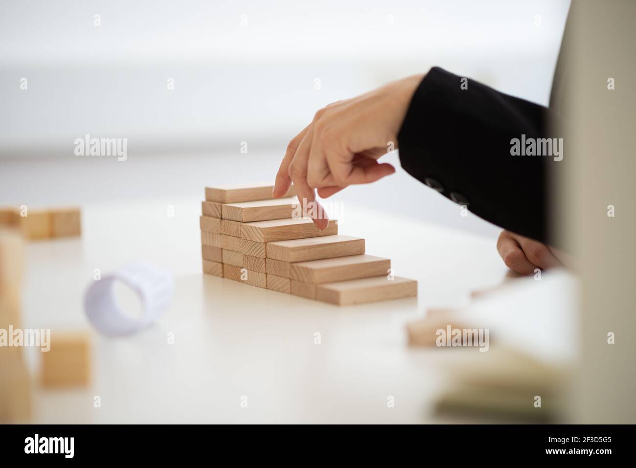 Nahaufnahme einer Geschäftsfrau, die mit den Fingern die konzeptionellen Schritte aus Holzblöcken hochläuft. Stockfoto
