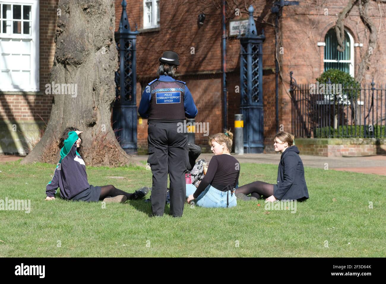Ein Polizeibeamter für die Unterstützung der Gemeinschaft ( PCSO ) Gespräche mit einer Gruppe von Teenagern saßen zusammen auf einem Sonniger Tag während der Coronavirus-Sperre in Hereford UK Stockfoto