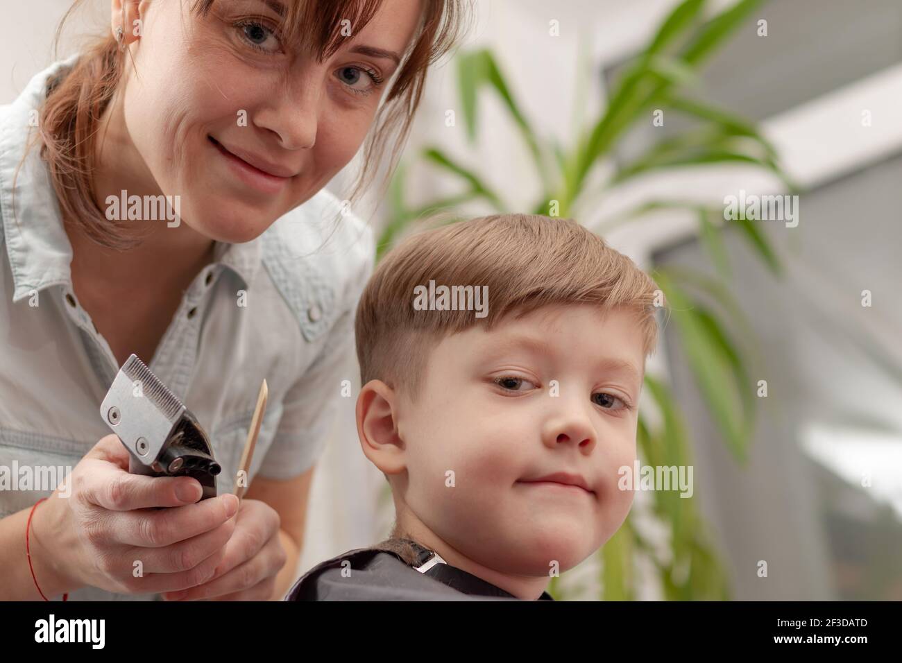 Junge Mutter Friseur schneidet ihr Baby Junge zu Hause mit Haarschneider während Quarantäne. Selektiver Fokus. Porträt Stockfoto