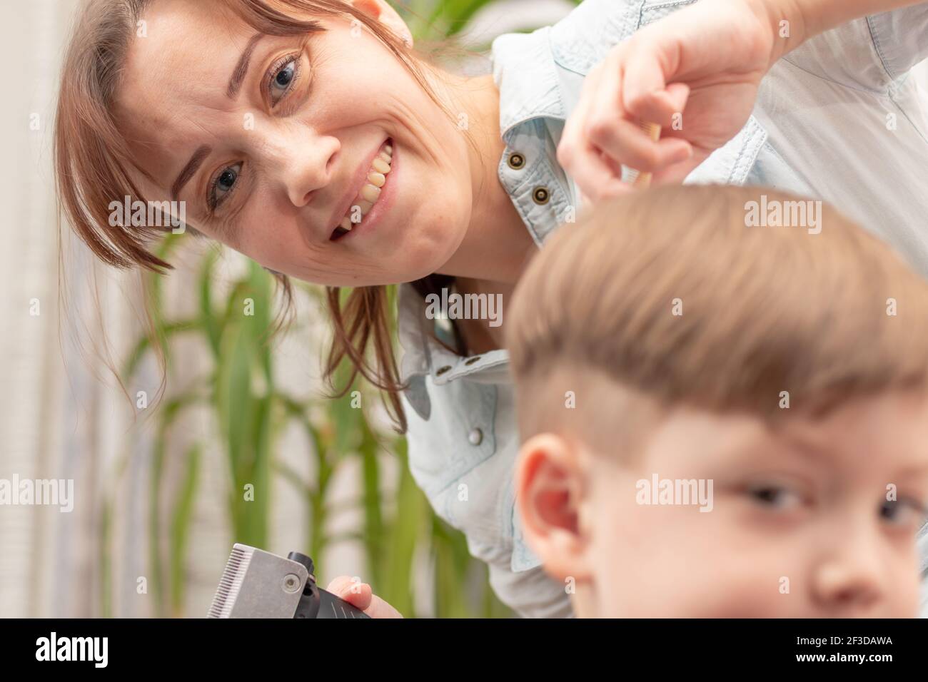 Junge Mutter Friseur schneidet ihr Baby Junge zu Hause mit Haarschneider während Quarantäne. Selektiver Fokus. Porträt Stockfoto