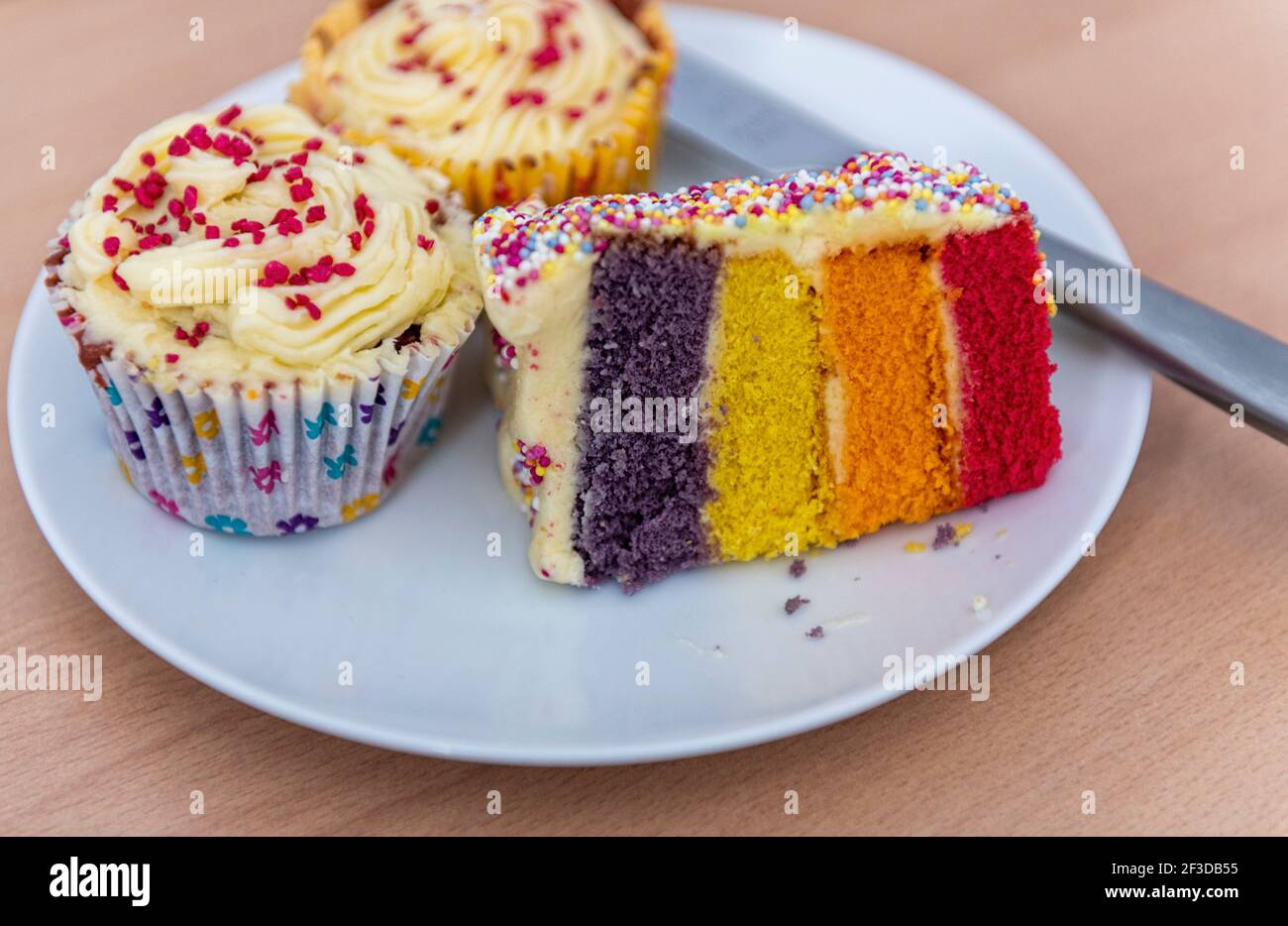 Regenbogen geschichteten Biskuitkuchen und Cupcakes Buttercreme Belag Stockfoto