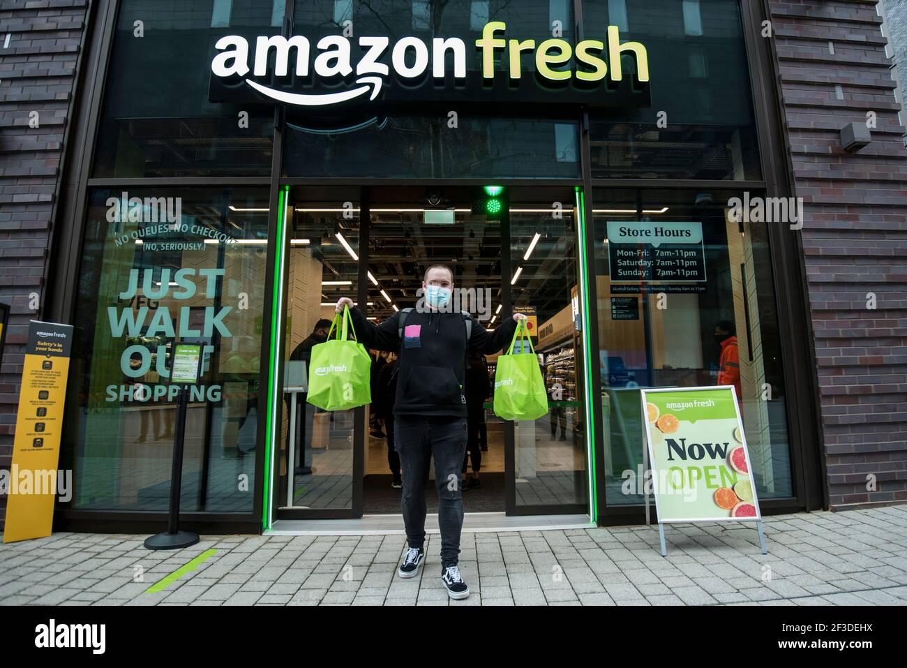 London, Großbritannien. 16. März 2021. Ein Kunde mit seinem Einkauf  außerhalb des neuen 2.500 qm großen Amazon Fresh Stores im Wembley Park,  West London, am Eröffnungstag. Es ist der zweite „Just Walk
