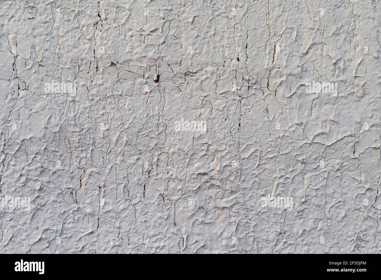 Weite Sicht auf eine stark erodierende und rissende Außenstuck weiß lackiert verputzte Wand. Stockfoto