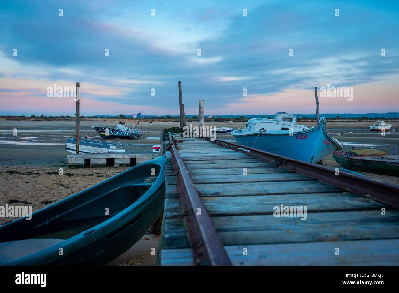 Low-Angle-Ansicht des Schienenpaares, das zum Starten des Bootes auf dem Wasser verwendet wird. Mehrere Boote am Strand bei Ebbe. Meeresküste. Stockfoto