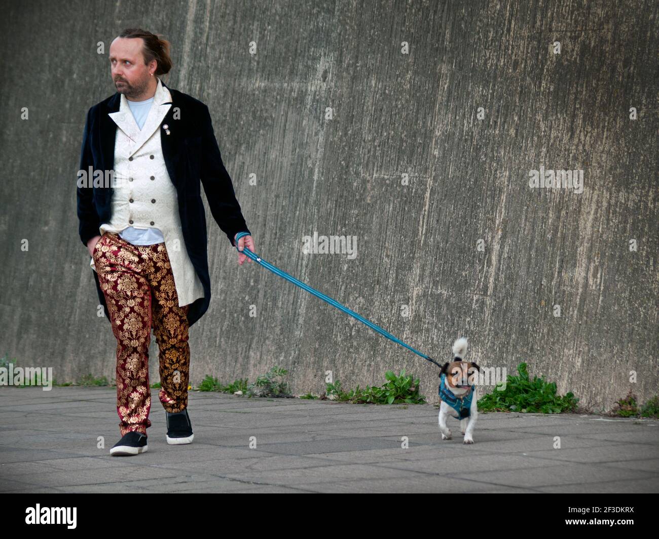 Ein stilvoll gekleideter Mann nimmt seinen Hund mit auf einen Spaziergang In Brighton Stockfoto