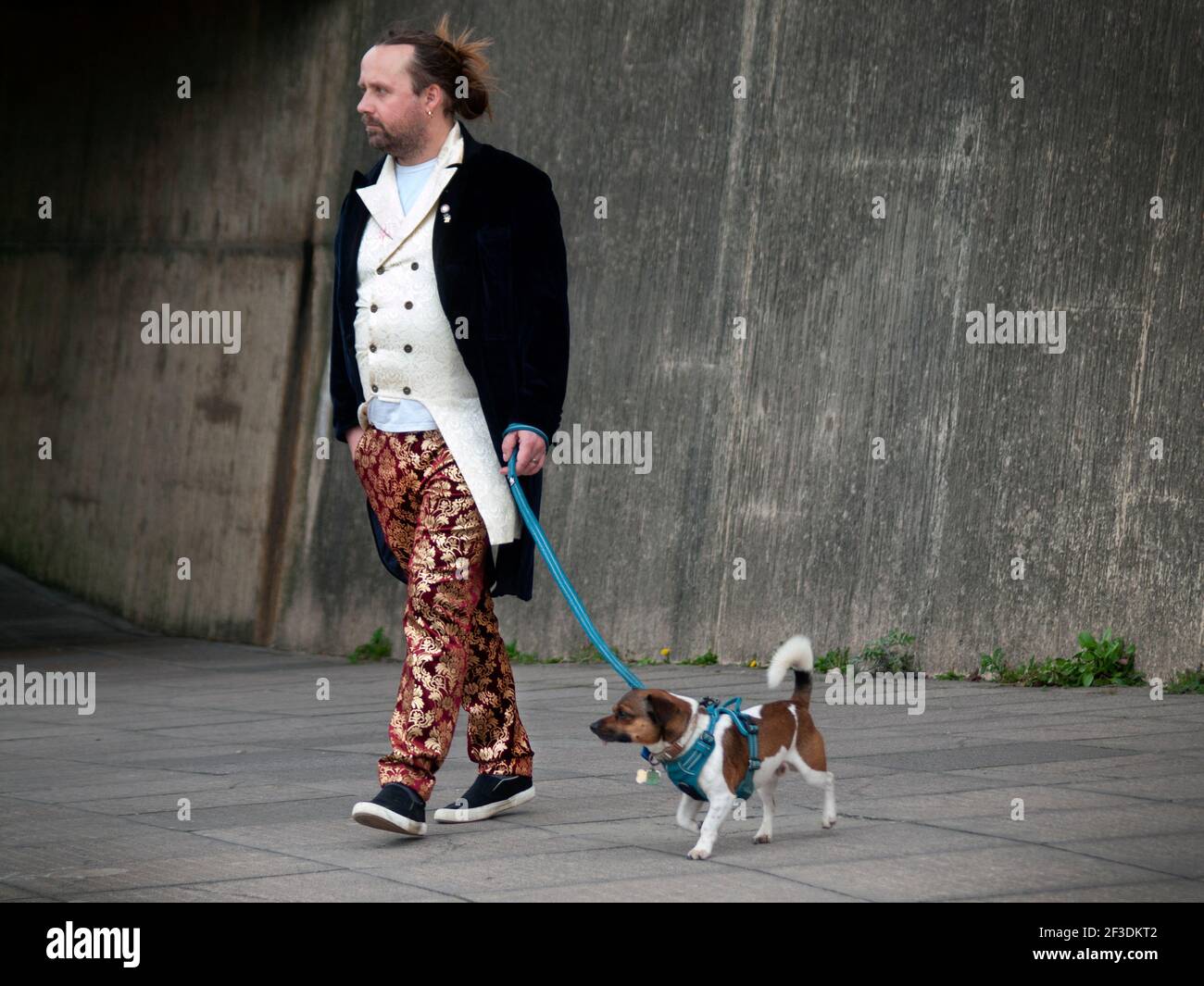 Ein stilvoll gekleideter Mann nimmt seinen Hund mit auf einen Spaziergang In Brighton Stockfoto