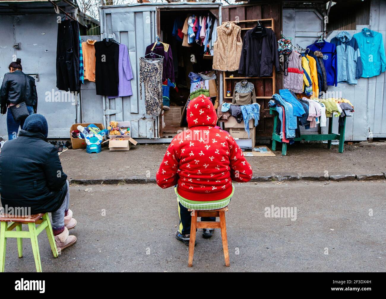 Non Exclusive: UZHHOROD, UKRAINE - 14. MÄRZ 2021 - auf dem Sonntagsflohmarkt im Radda sitzen Verkäufer vor einem Container mit gebrauchten Kleidern Stockfoto