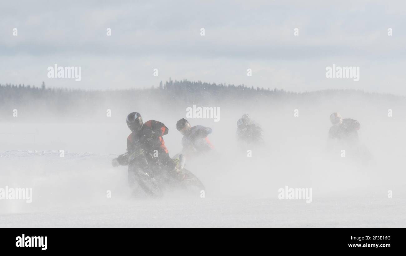 Ein Motorradfahrer, der auf einer Eisbahn in der Mitte rast Von wirbelndem Schnee Stockfoto
