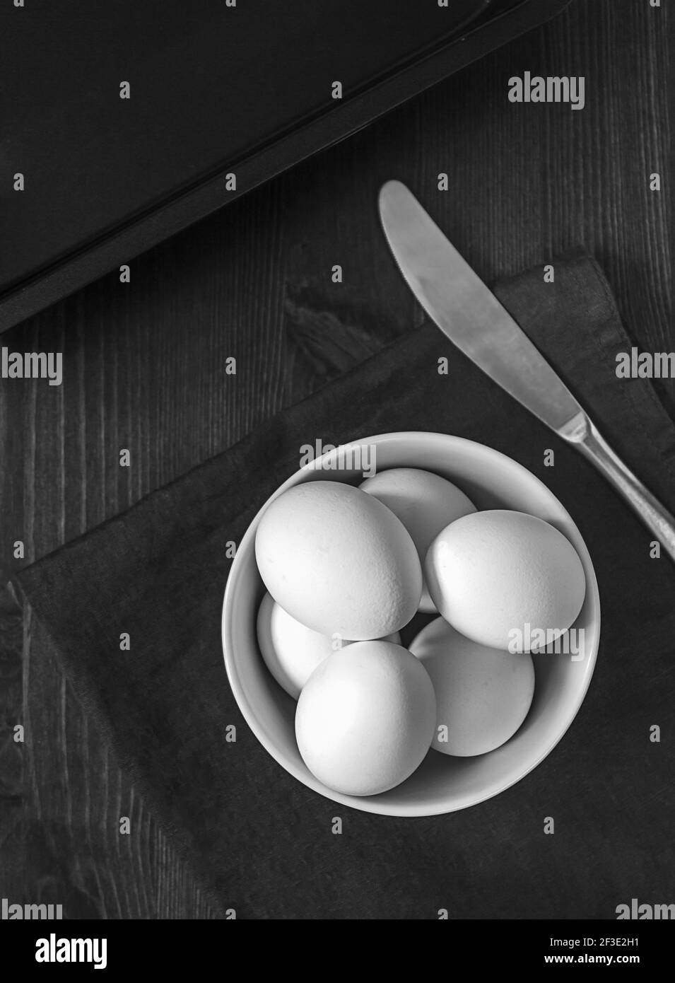 Das Konzept der einfachen gesunden natürlichen Lebensmittel. Hühnchen, weiße, frische Bauerneier in einer weißen Schüssel, die auf dunklem Holzhintergrund ein Omelett kochen. Stockfoto