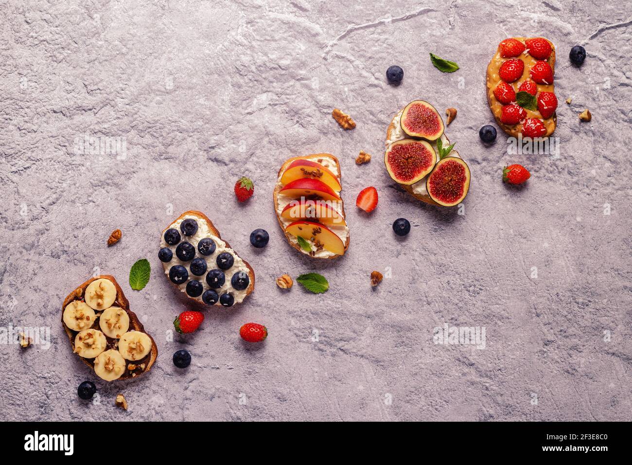 Hausgemachter Sommertoast mit Frischkäse, Nussbutter und Früchten und Beeren, Draufsicht. Stockfoto