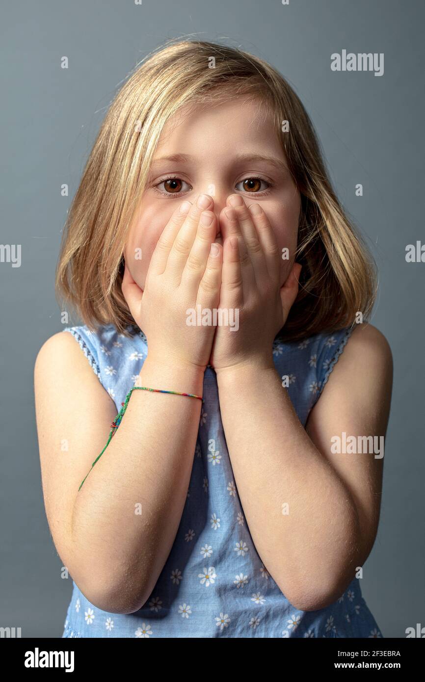 5 Jahre altes kaukasisches Mädchen mit Händen, die ihr Gesicht bedecken. Stockfoto