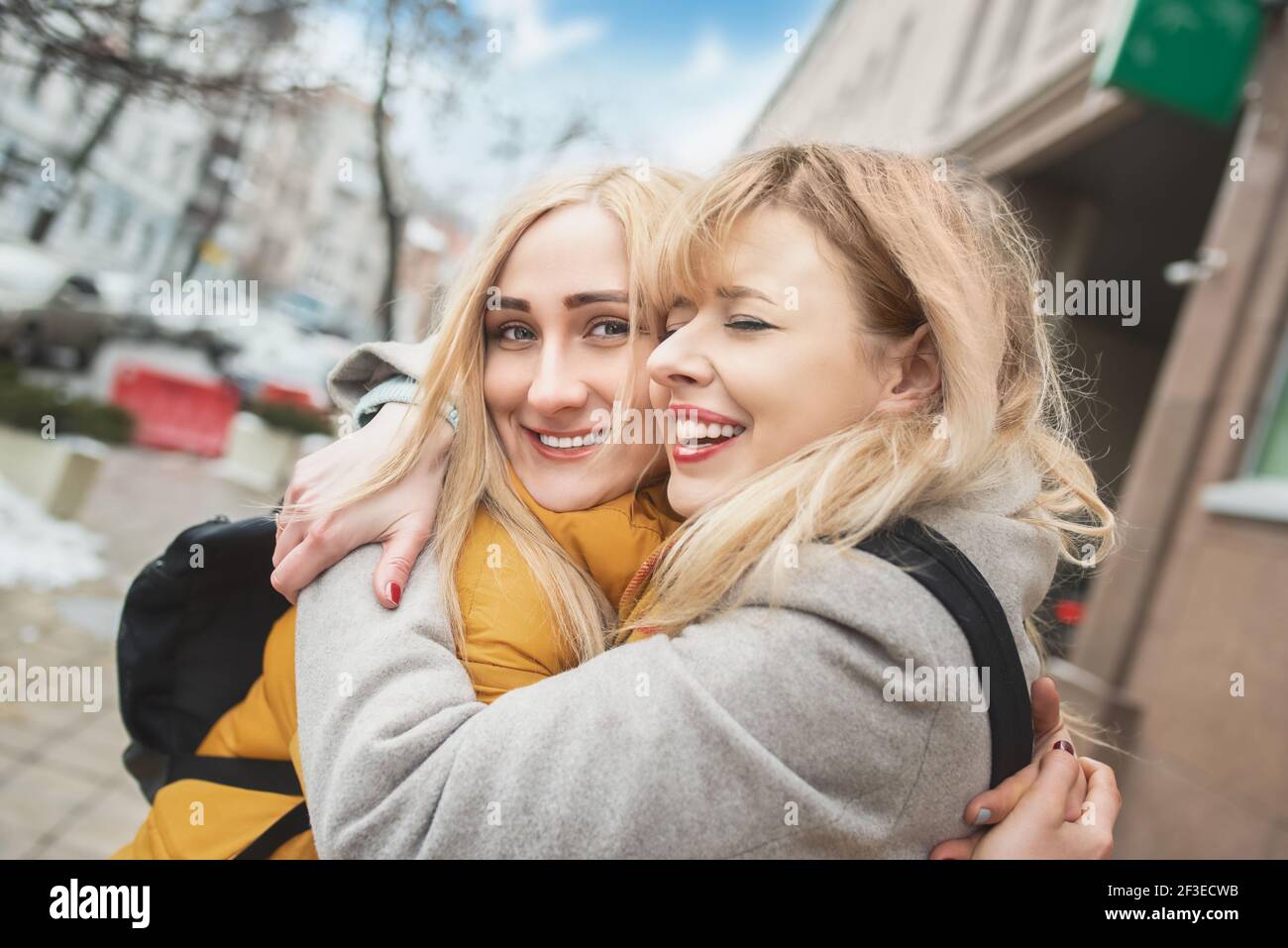 Zwei junge Frauen gehen auf der Straße und lachen. Beste Freunde. Gegen die Sonne Stockfoto