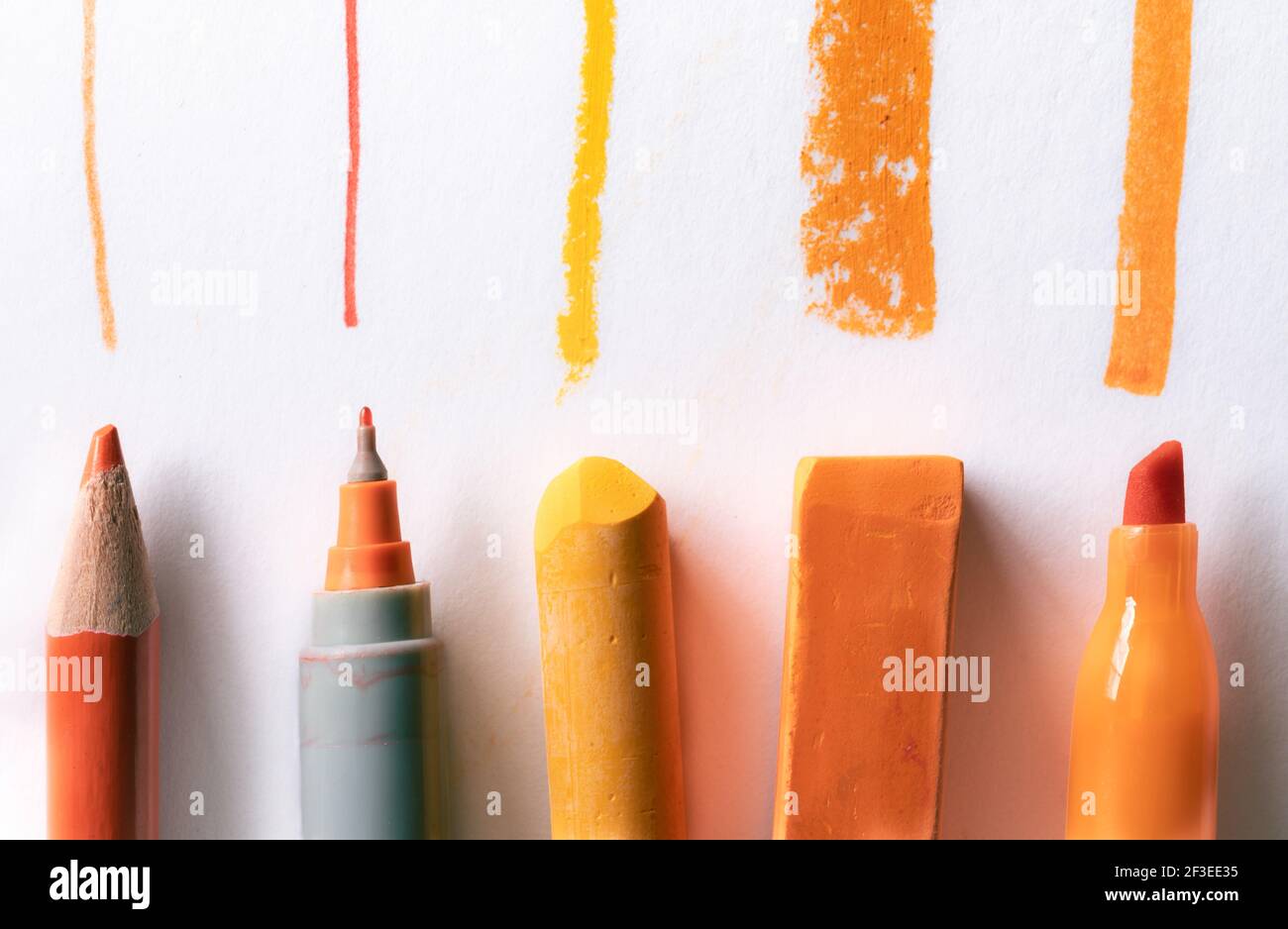 Orangefarbener Bleistift, Stift, Pastell und Markierungslinien auf weißem Hintergrund Stockfoto