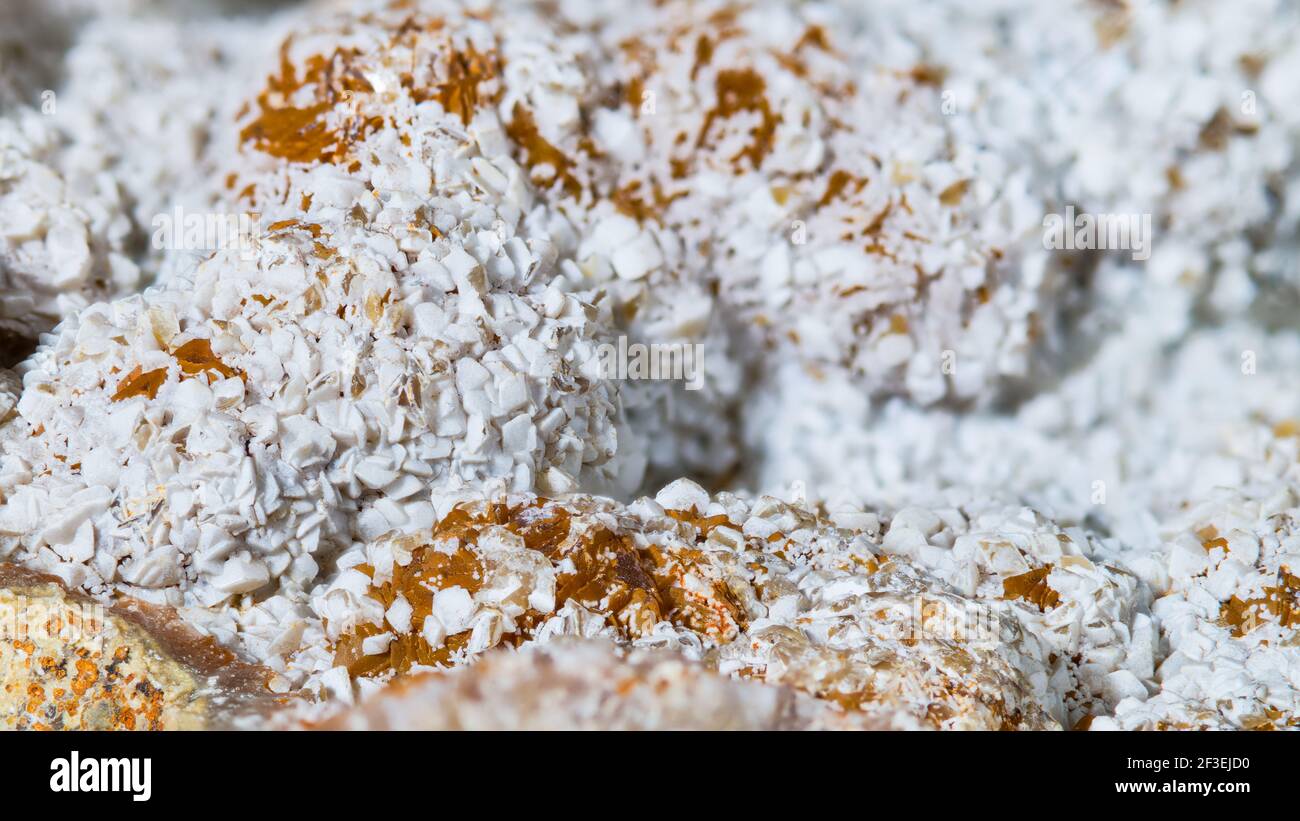 Weiße und orange Cluster von Kristallen auf Aragonit Mineral in Textur Detail. Nahaufnahme von Calciumcarbonat Kristallform. Mineralogie. Sammlerstück. Stockfoto