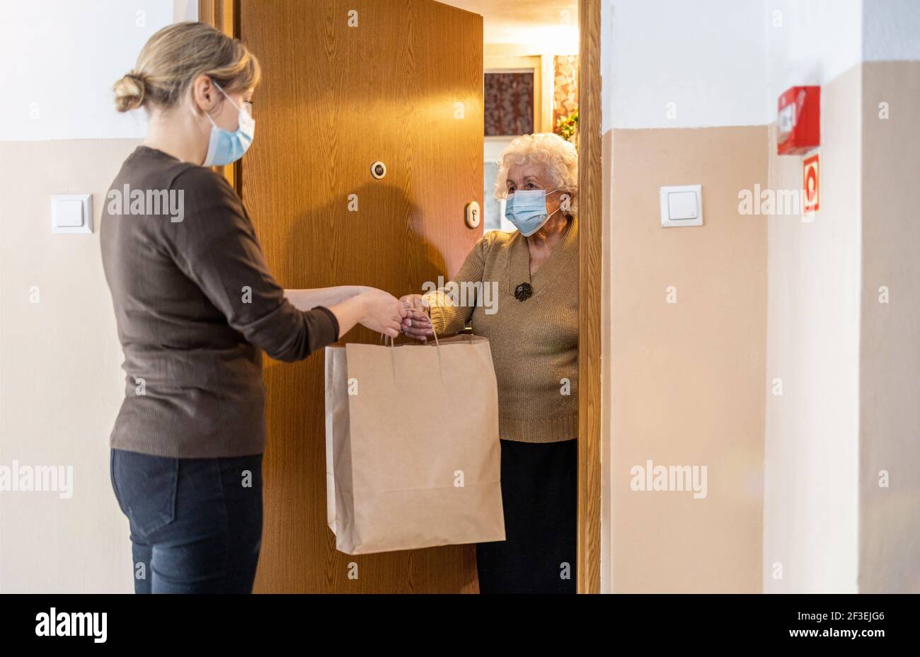 Weibliche Freiwillige Lieferung Taschen mit Einkaufen an ältere Frau während Coronavirus-Pandemie Stockfoto