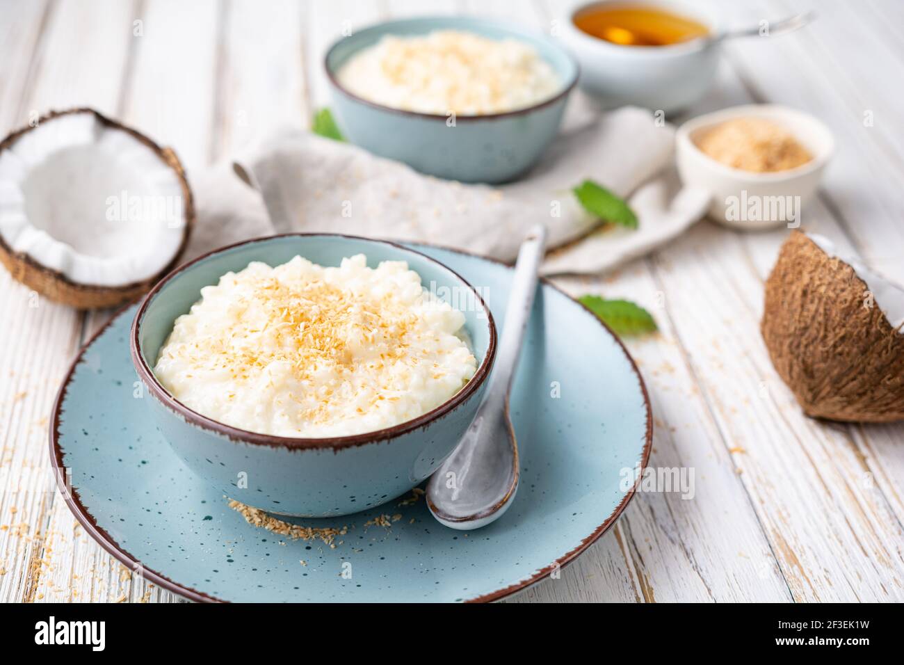 Süßer und cremiger Kokosnusspudding mit Honig, gekrönt mit geriebener und gerösteter Kokosnuss in einer Keramikschale Stockfoto