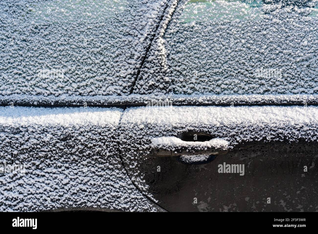 Auto mit Eis und Eiszapfen nach Glatteisregen bedeckt. Eisbedecktes Autofenster aus der Nähe. Schlechtes Winterwetter, EissturmWinter frostige Szenen. Stockfoto