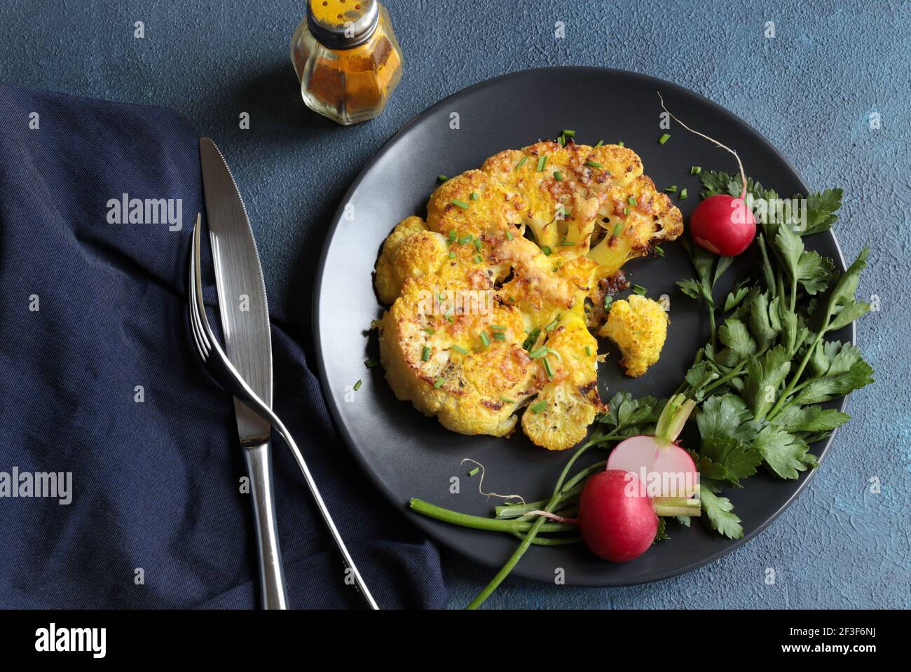 Blumenkohlsteak mit Kräutern und Gewürzen auf dunklem Hintergrund. Nahaufnahme. Stockfoto