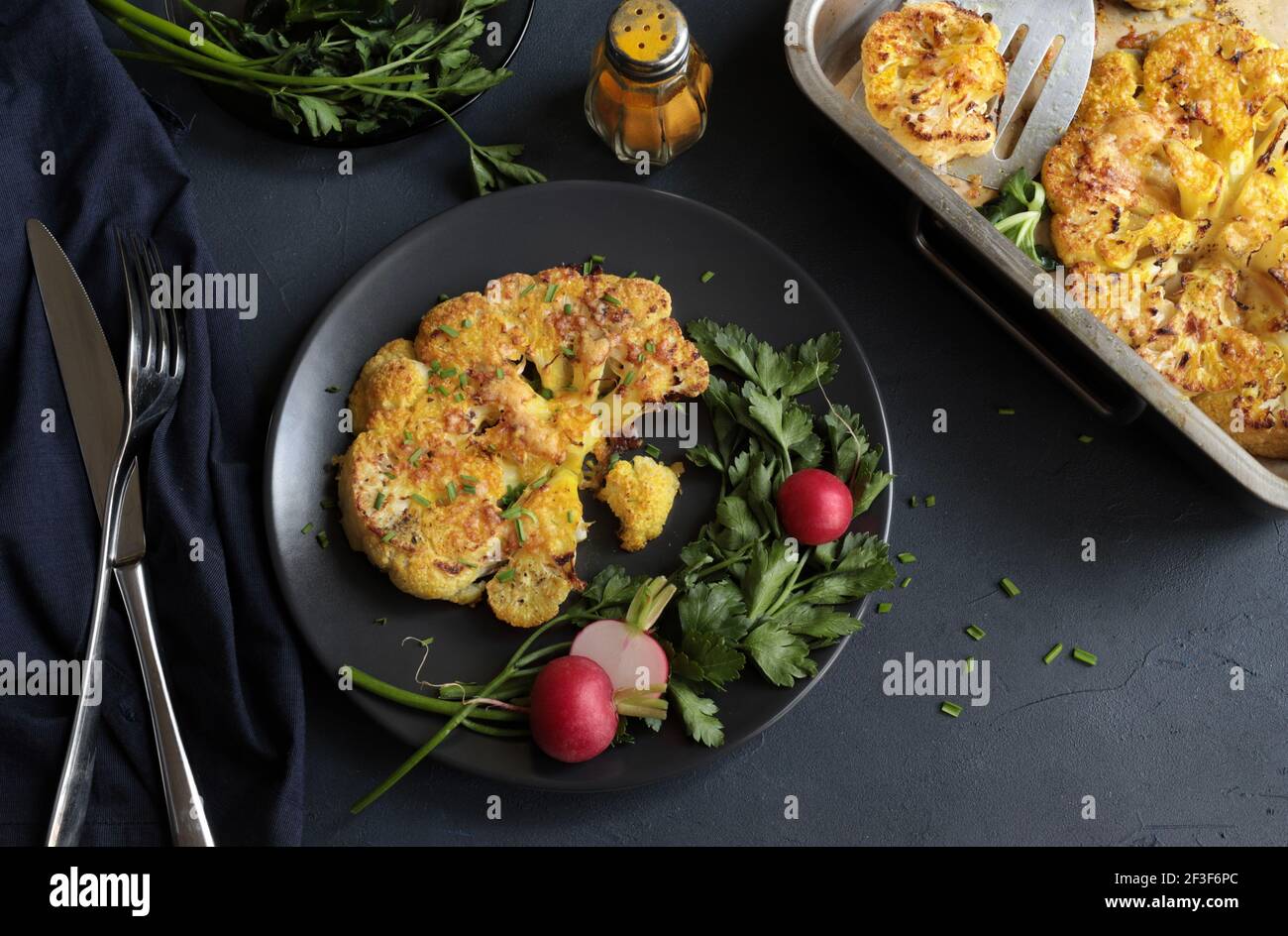Blumenkohlsteak mit Kräutern und Gewürzen auf dunklem Hintergrund. Nahaufnahme. Stockfoto