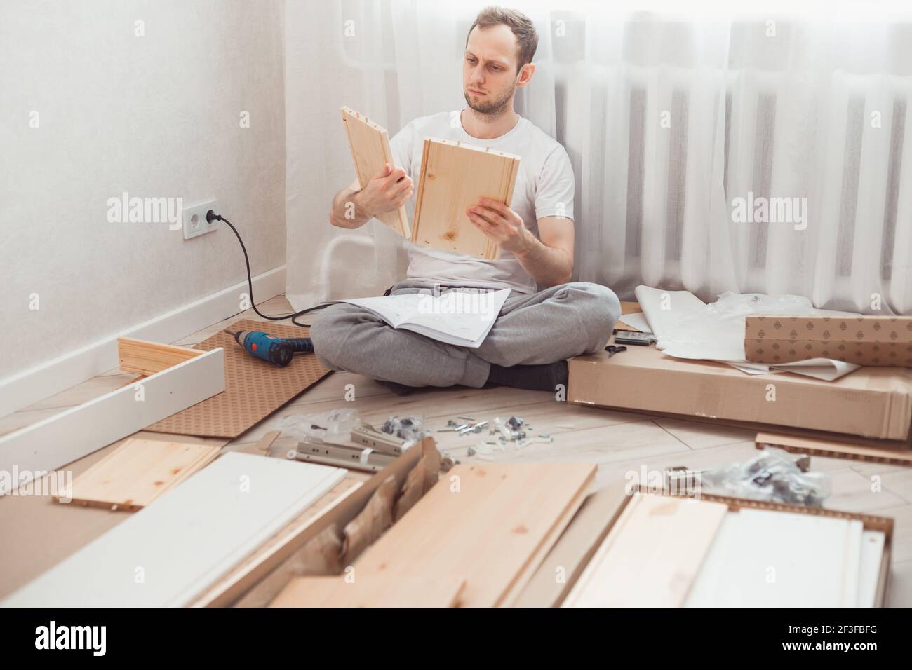 Mann selbst Baugruppen Holzmöbel zu Hause ohne Meister. Lesen Sie die Anweisungen. DIY-Konzept Stockfoto