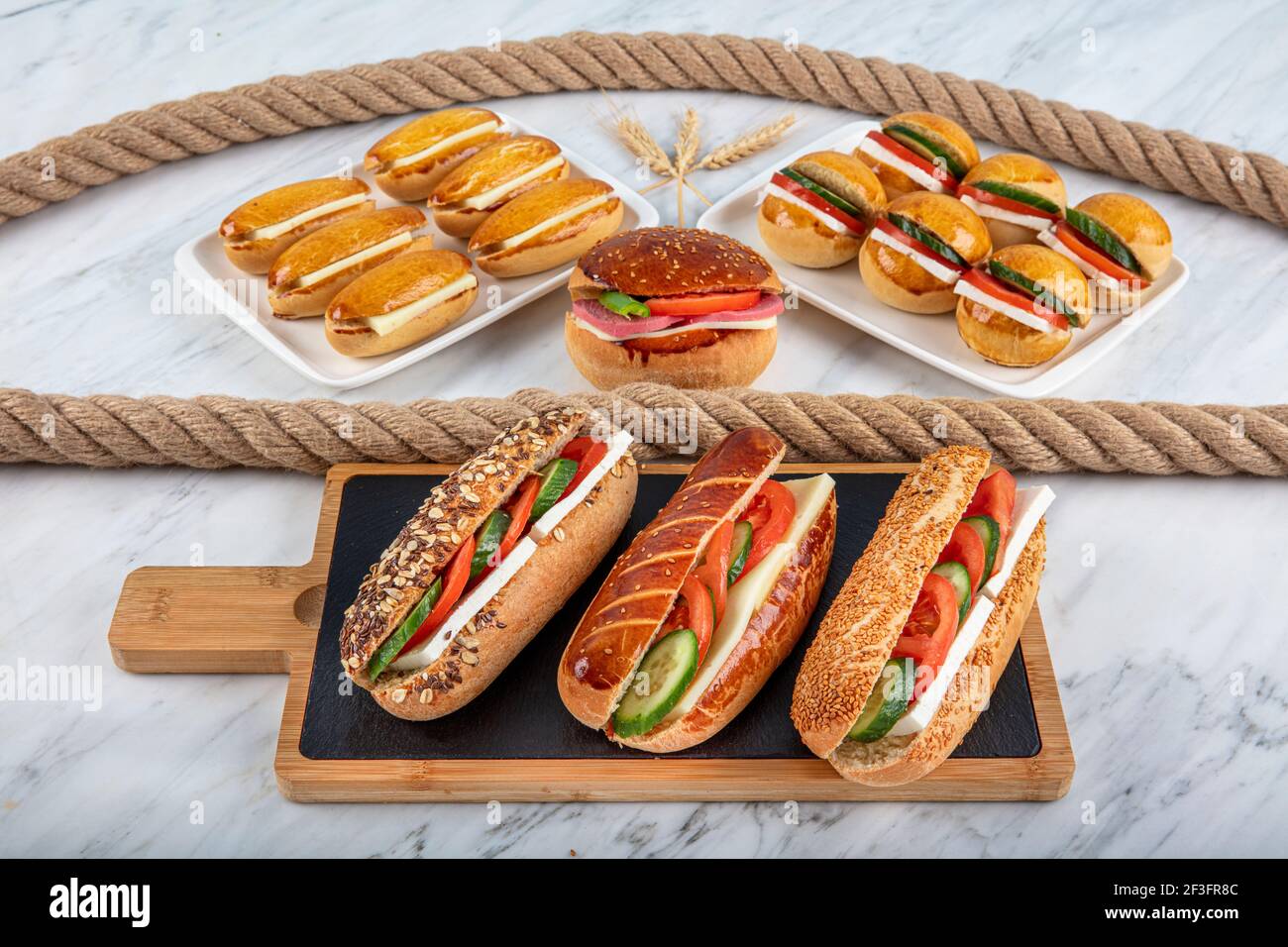 Verschiedene Sandwiches an einem Ladentisch. Sandwich mit Käse, Gurke und Tomate auf Schneidebrett. Stockfoto