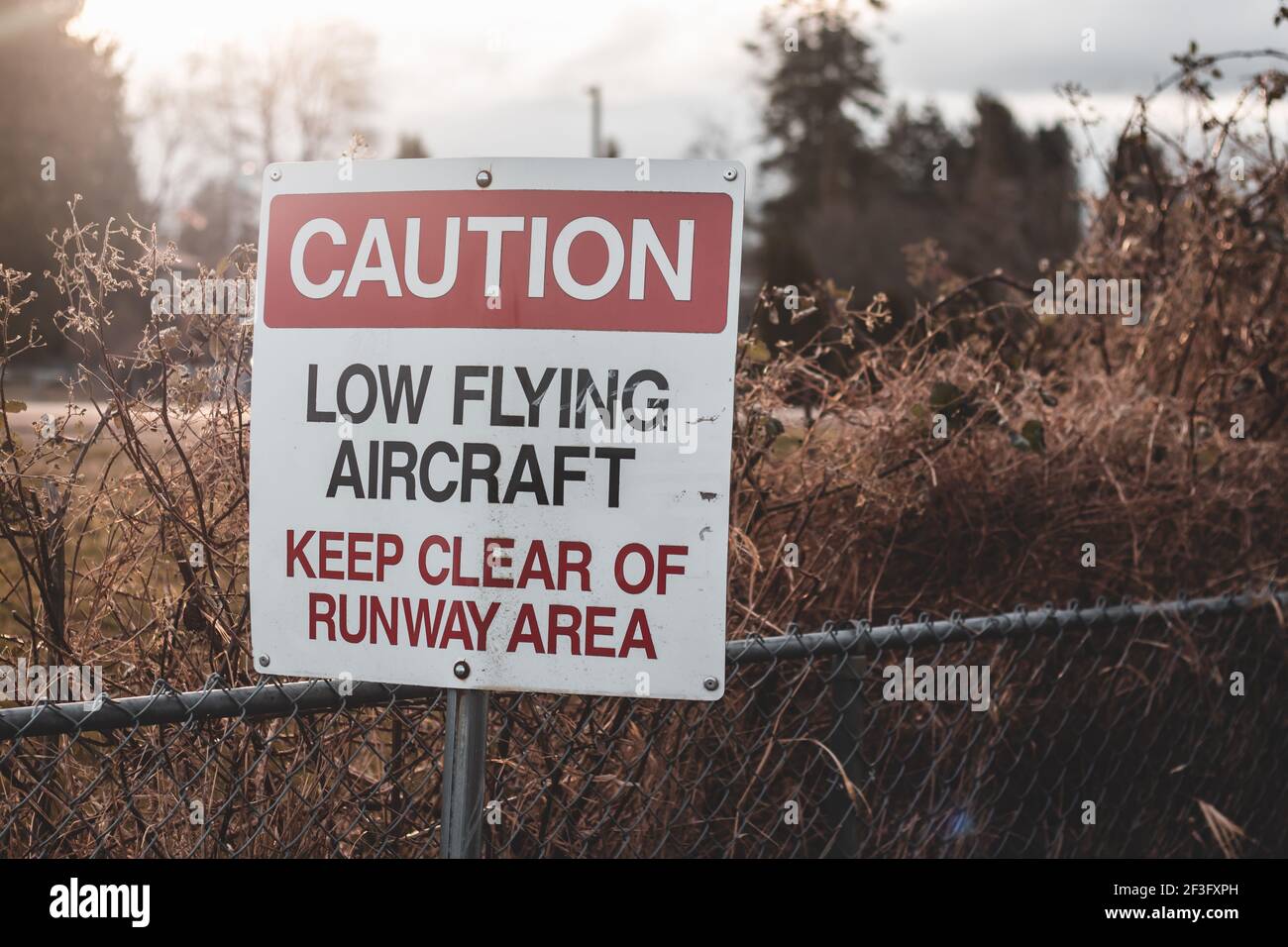 Blick auf das Schild Vorsicht Low Flying Aircraft am lokalen Flughafen in Courtenay, Kanada Stockfoto