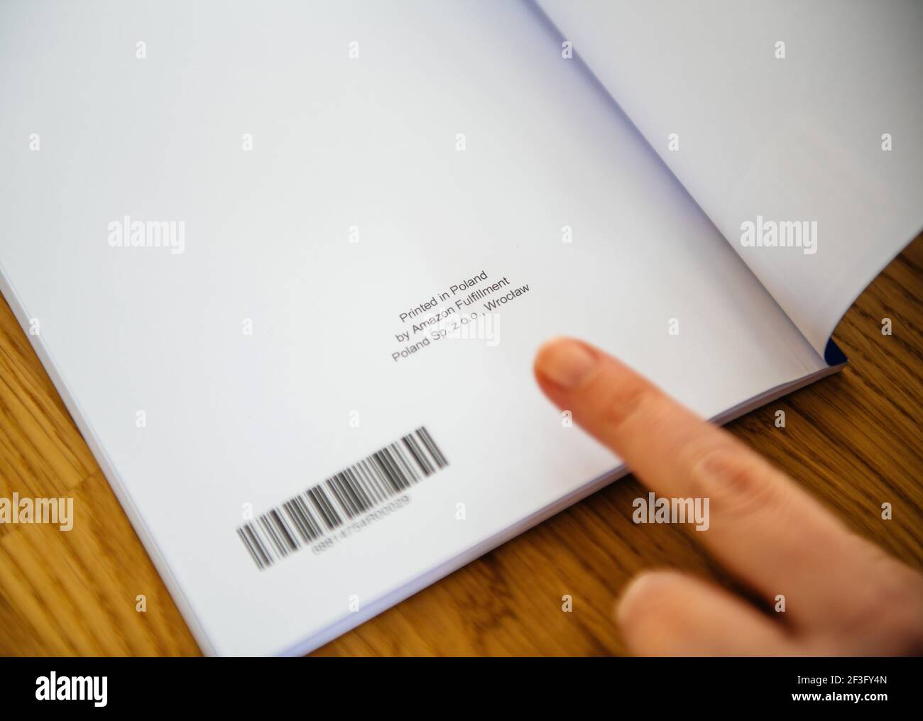 POV Frau zeigt mit dem Finger den Text an der Ende des Buches gedruckt in Polen von Amazon Versand Polen SP z oo Wroclaw - Selbstveröffentlichung Stockfoto