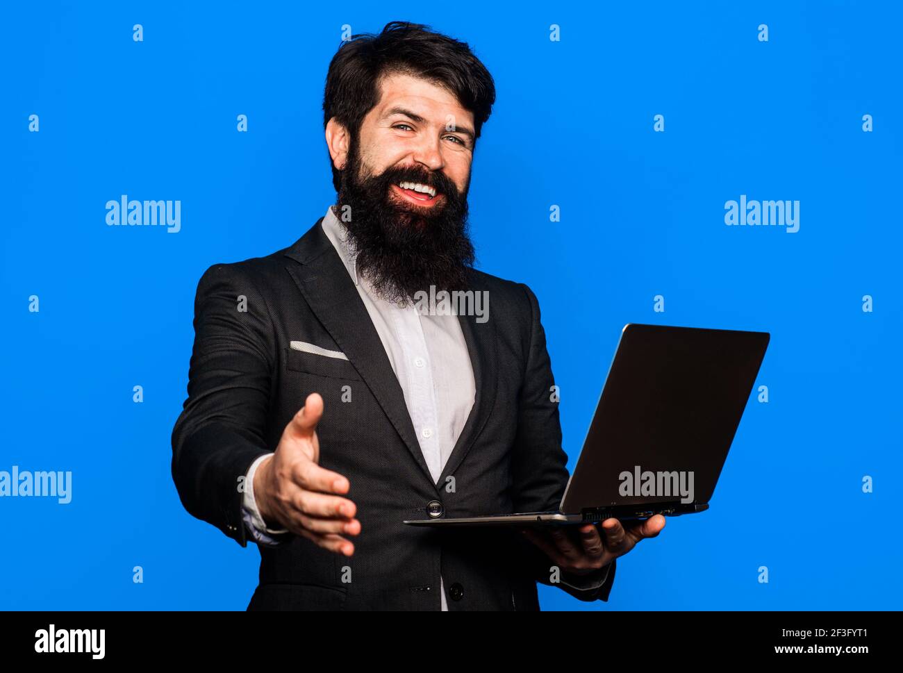 Willkommen Geschäft. Händedruck. Geschäftsmann mit Schüttelhände. Geschäftsleute in Meetings. Lächelnder bärtiger Mann mit Laptop. Stockfoto