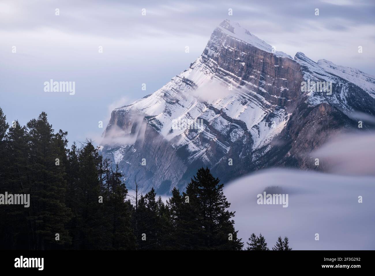 Eine lange Exposition der Wolke und des Nebels, die sich um den Berg Rundle und den Tunnel Mountain in der unteren rechten Ecke bewegen. Stockfoto